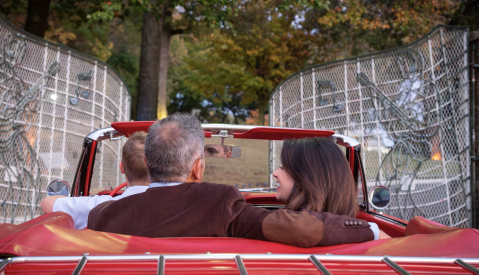 couple sits in red convertible driving through Graceland gates