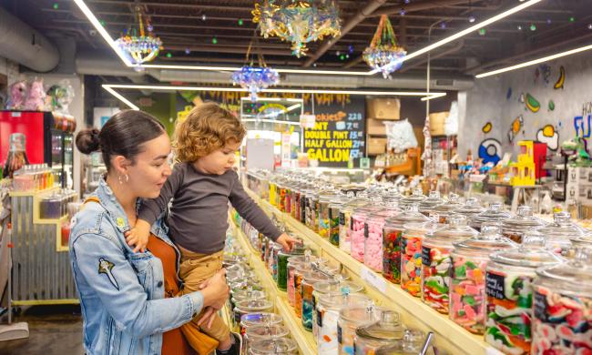 Woman holds child in candy shop Sweet Noshings