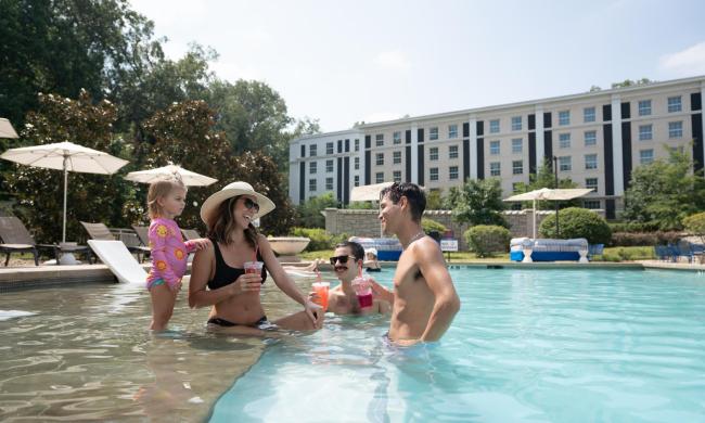 Guests — a child and three adults — gathered at the pool at Guest House at Graceland.