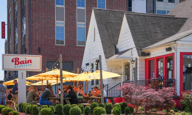 people dining under yellow umbrellas on the patio at Bain Barbecue