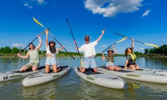 group of paddle boarders pose for photo holding up oars on boards